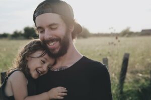 Papá abrazandd a niña en campo soleado